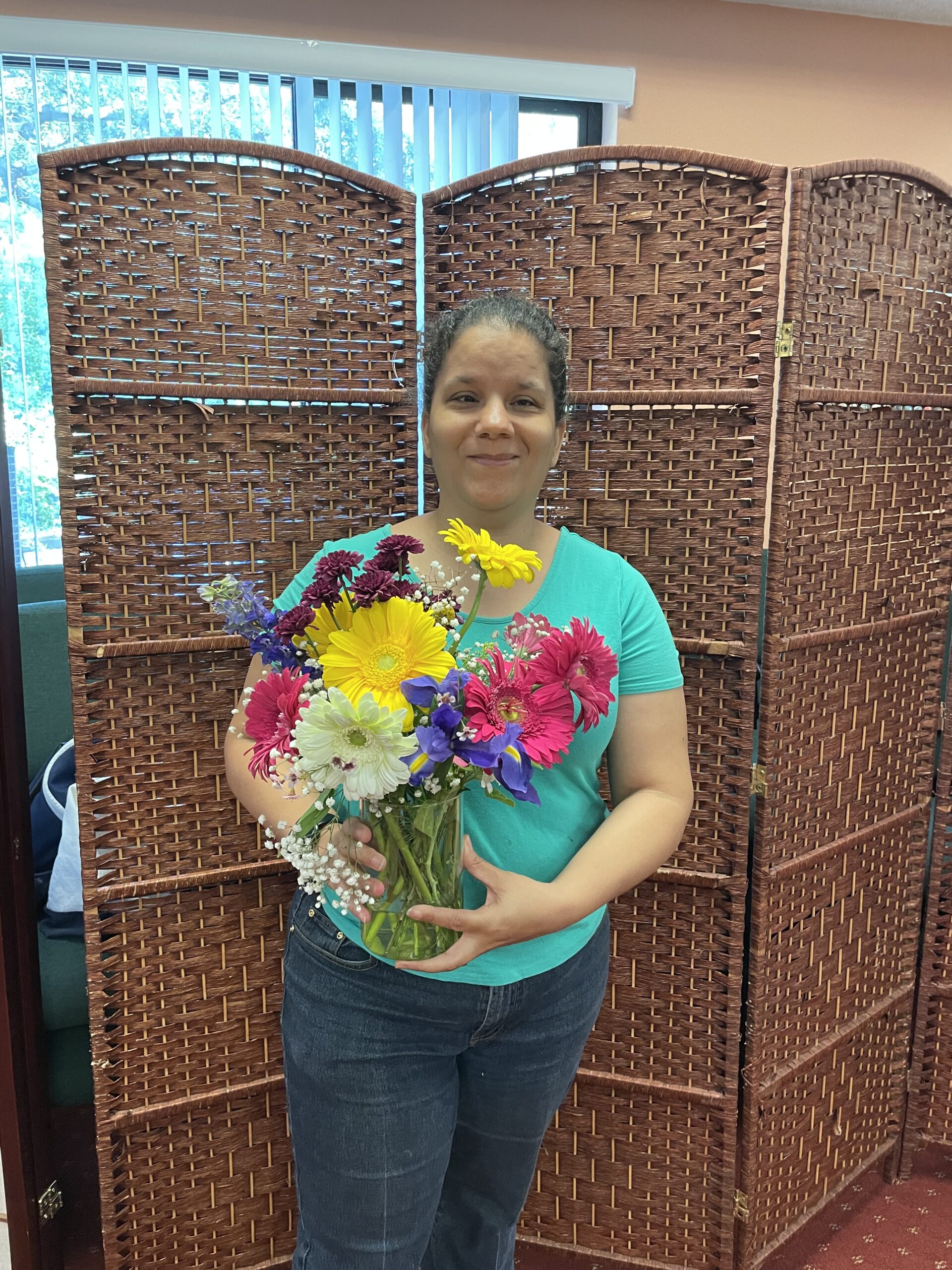 Rev. Christy Ann Clark smiling and holding a bouquet of colorful flowers